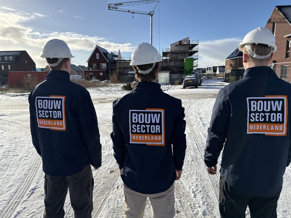 Drie vakmensen van Bouwsector Nederland met witte bouwhelm bij woningen in aanbouw